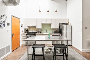 A modern kitchen with stainless steel appliances, a central island with stools, and pendant lighting. - Pet Friendly | King Bed | Beltline Access (Atlanta)