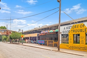 A street scene with a yellow building labeled "A History of Good Trouble" and a sign for "Mercado" with a blue storefront. - Pet Friendly | King Bed | Beltline Access (Atlanta)