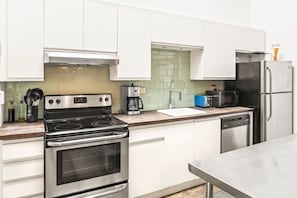 A modern kitchen with white cabinets, stainless steel appliances, a coffee maker, and a toaster. - Pet Friendly | King Bed | Beltline Access (Atlanta)