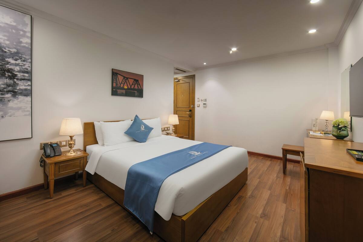 Una habitación de hotel con una cama, mesitas de noche, un escritorio y una silla.