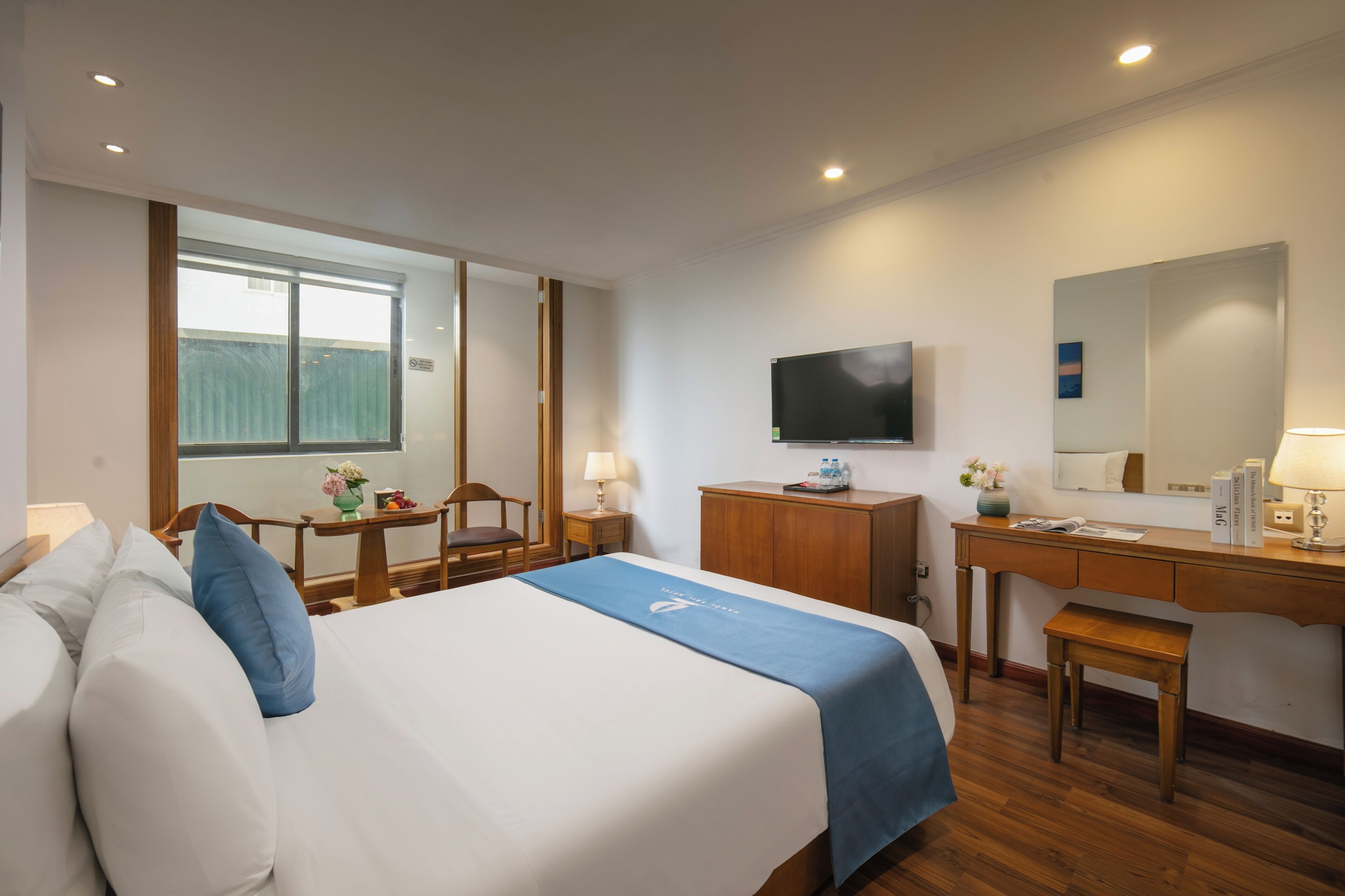 A hotel room with a bed, a desk, a chair, a TV, and a window.