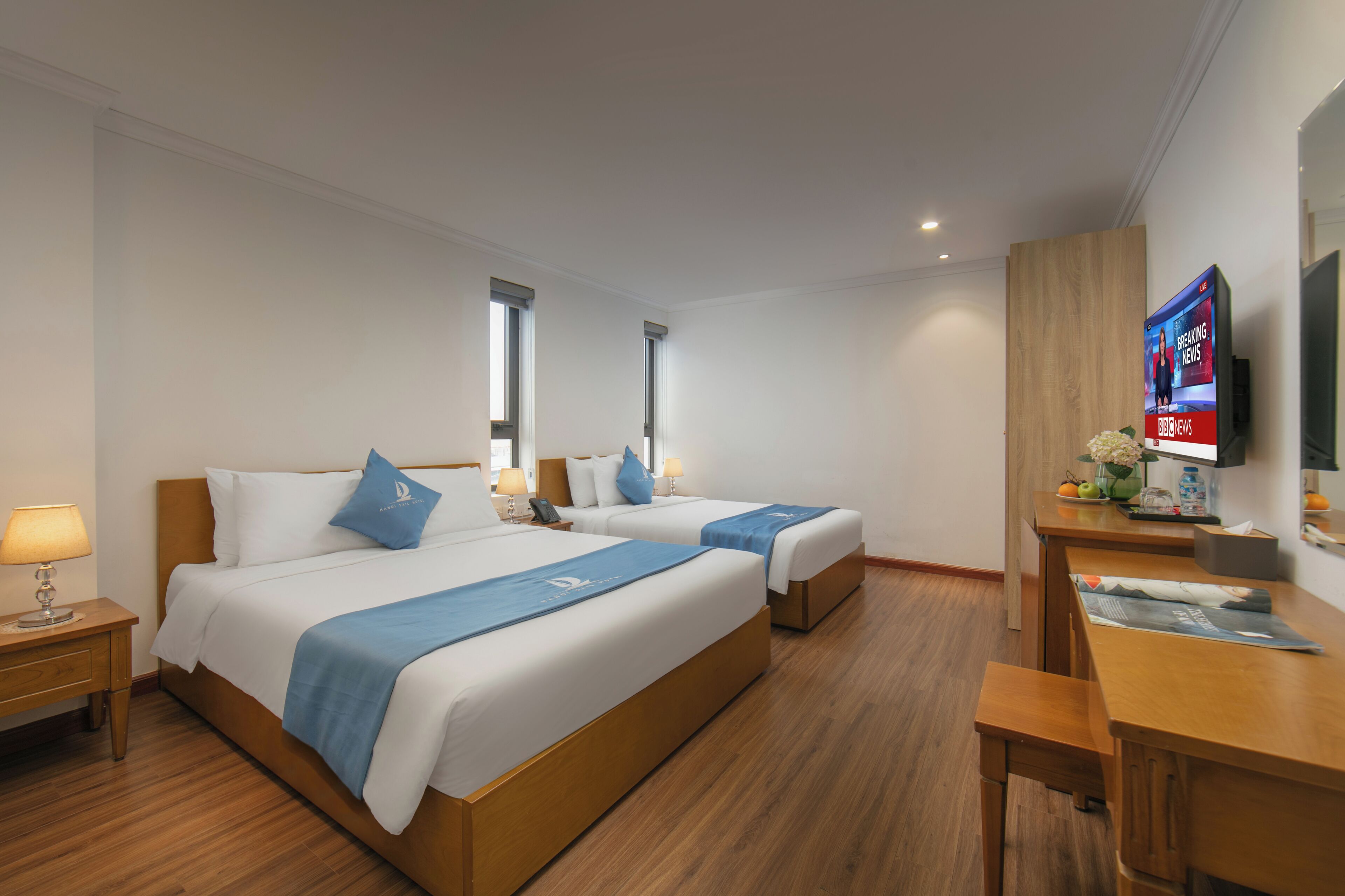 Una habitación de hotel con dos camas, un escritorio, un televisor y una ventana.