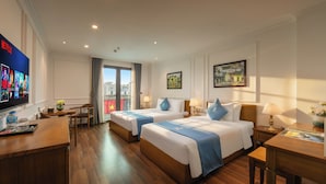 Une chambre d’hôtel avec deux lits, un bureau, un téléviseur diffusant du contenu Netflix et une vue sur la ville.