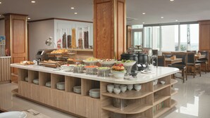 Un buffet proposant une variété de plats, un coin café et un espace détente avec des tables et des chaises.
