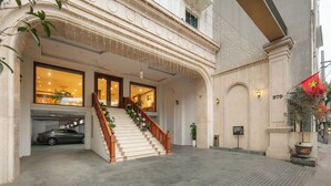 Une grande entrée avec un escalier, une voiture garée dans un garage et un drapeau à droite.