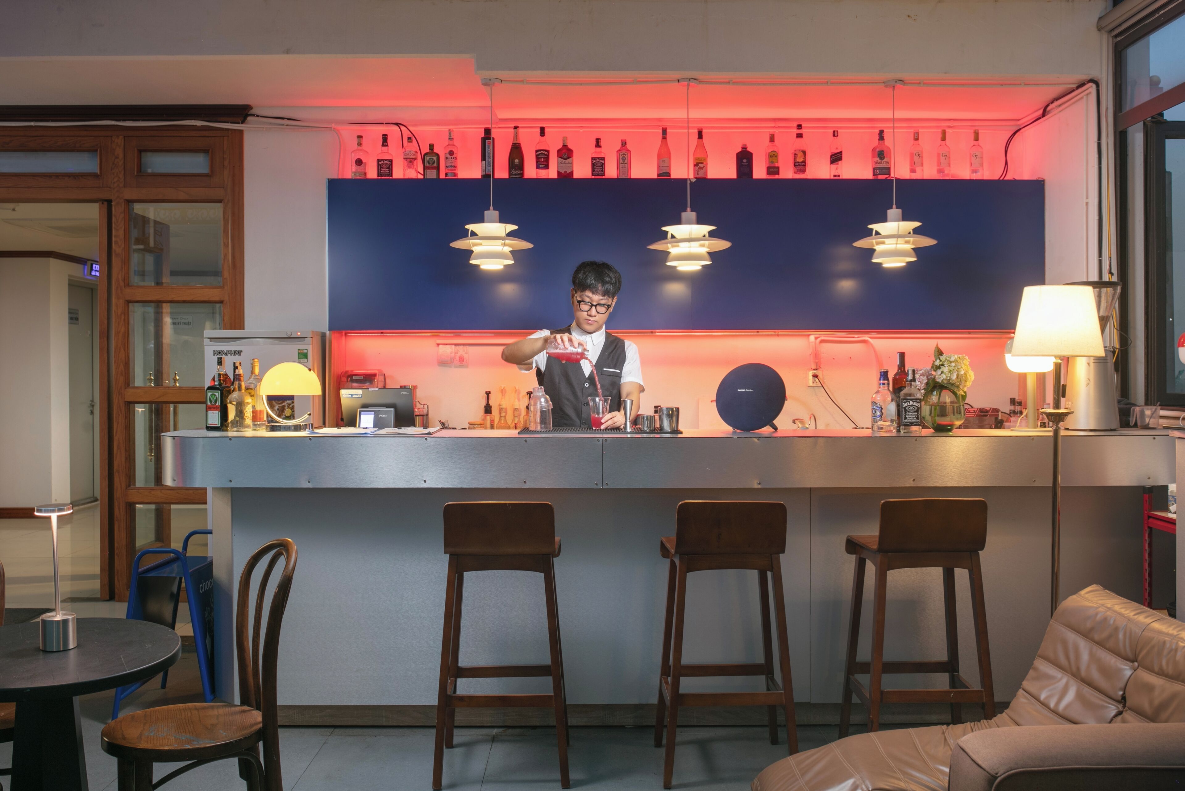 Una zona de bar con taburetes, una barra y un cantinero.