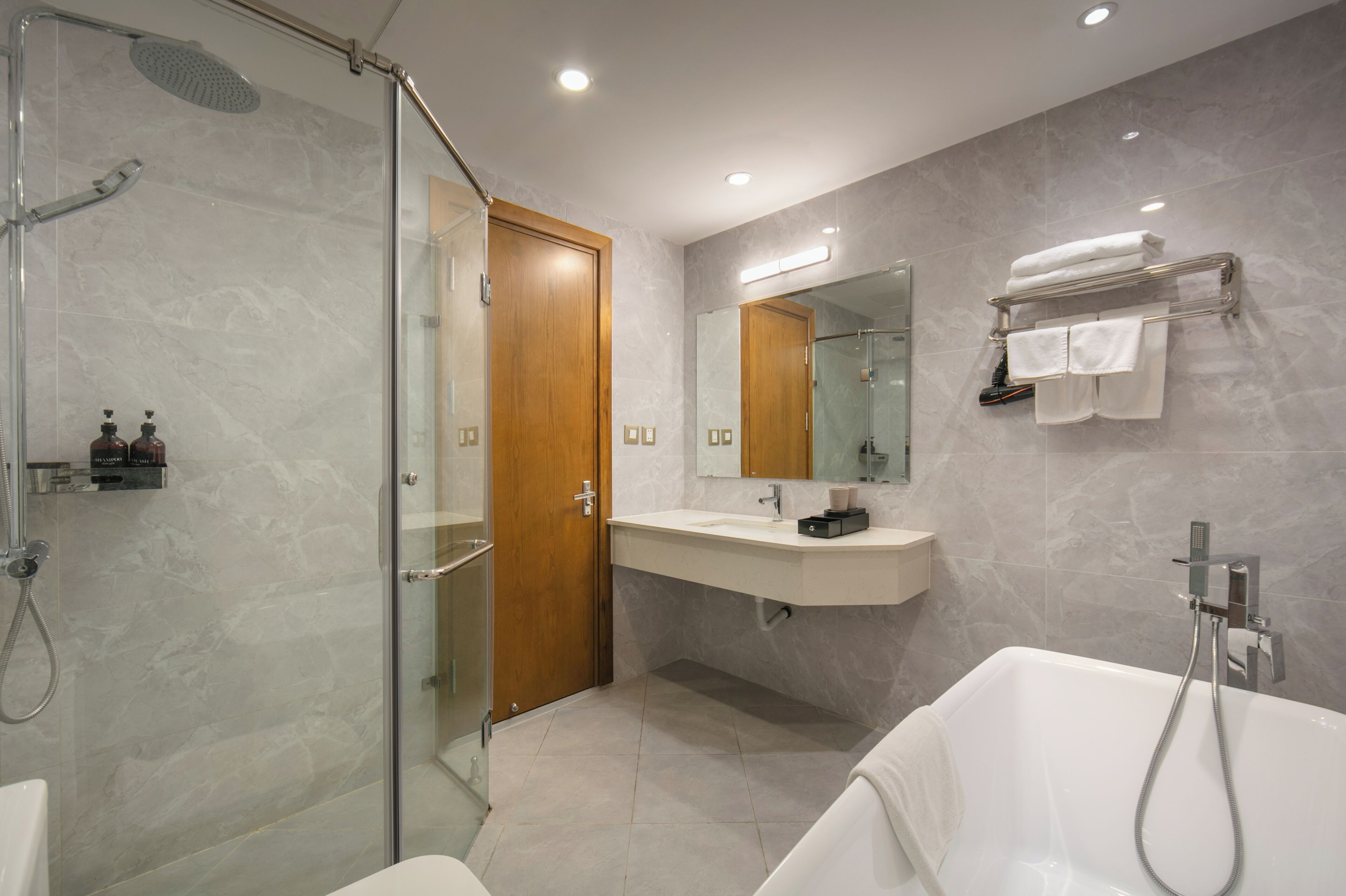 A modern bathroom with a glass-enclosed shower, a vanity with a mirror, and a bathtub.