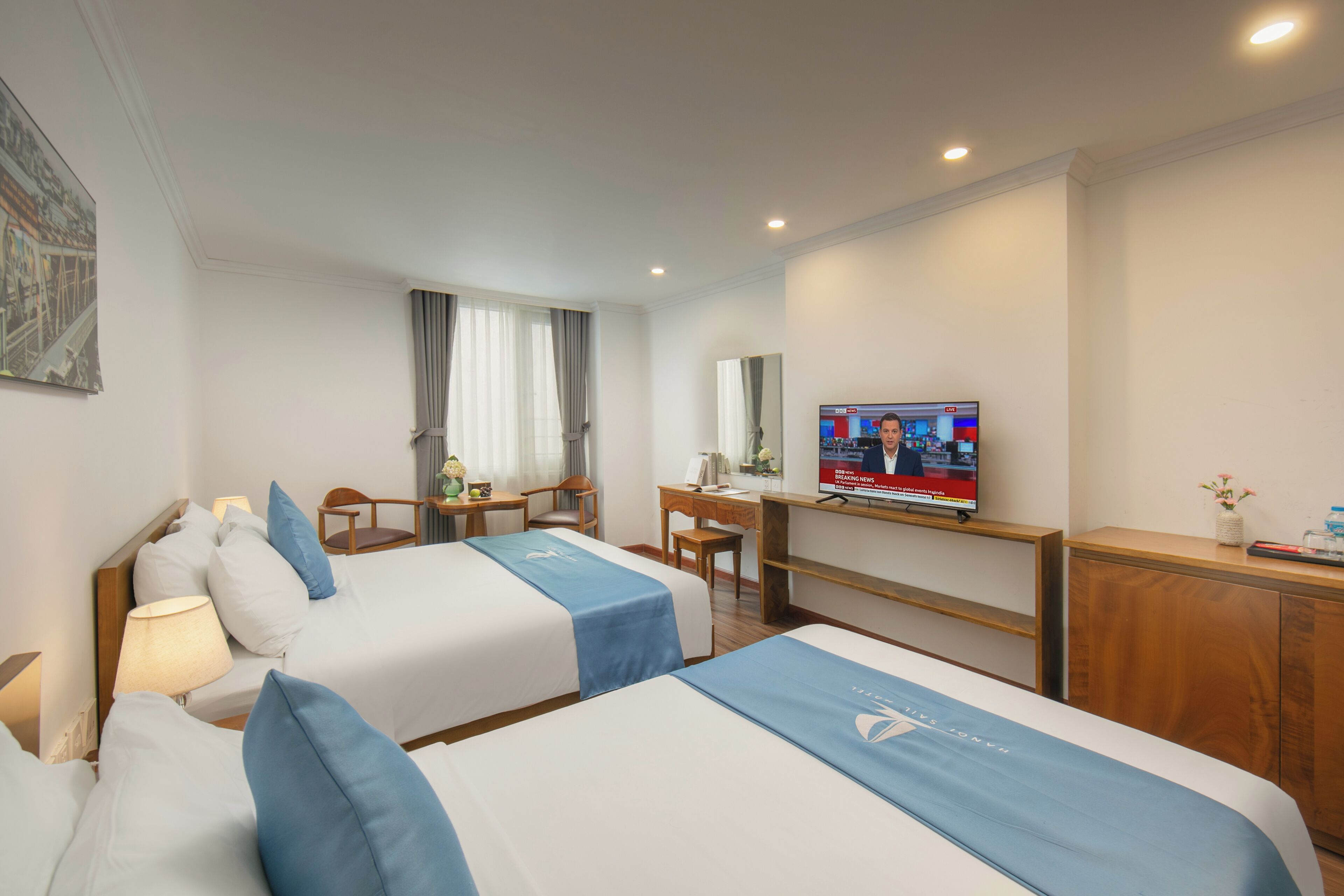Ein Hotelzimmer mit zwei Betten, einem Schreibtisch, einem Fernseher und einem Spiegel.