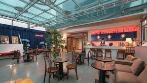 Un vaste espace intérieur aménagé avec des tables et des chaises, un coin bar et un grand plafond en verre.