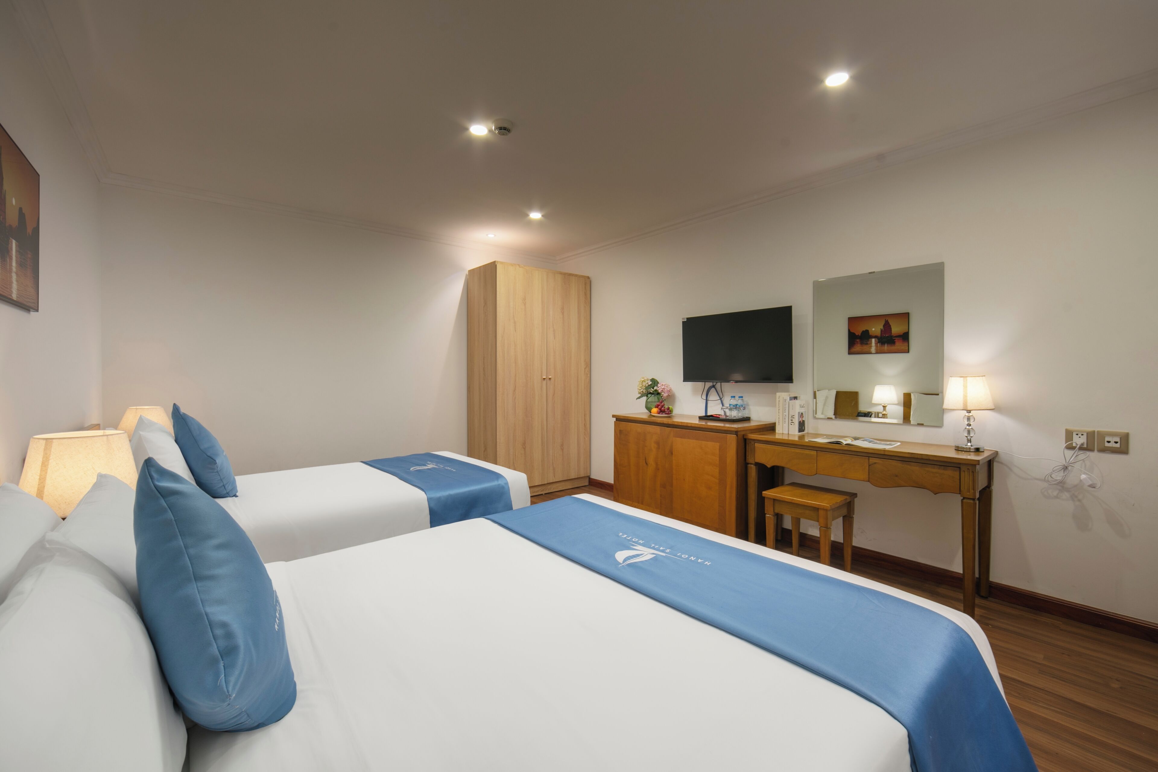 Una habitación de hotel con dos camas, un escritorio, un armario, un televisor y una lámpara.