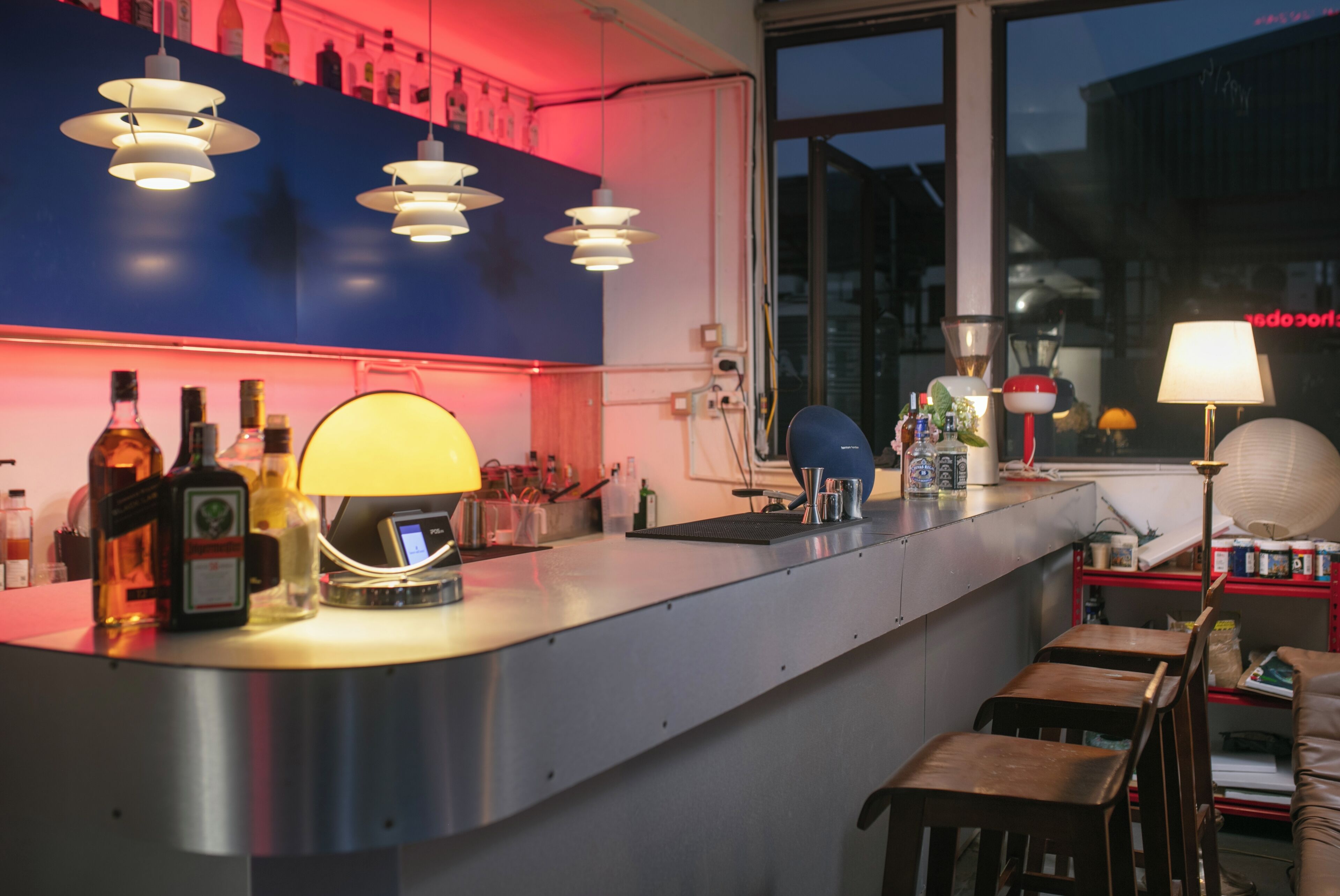 A bar area with a counter, stools, and various bottles.