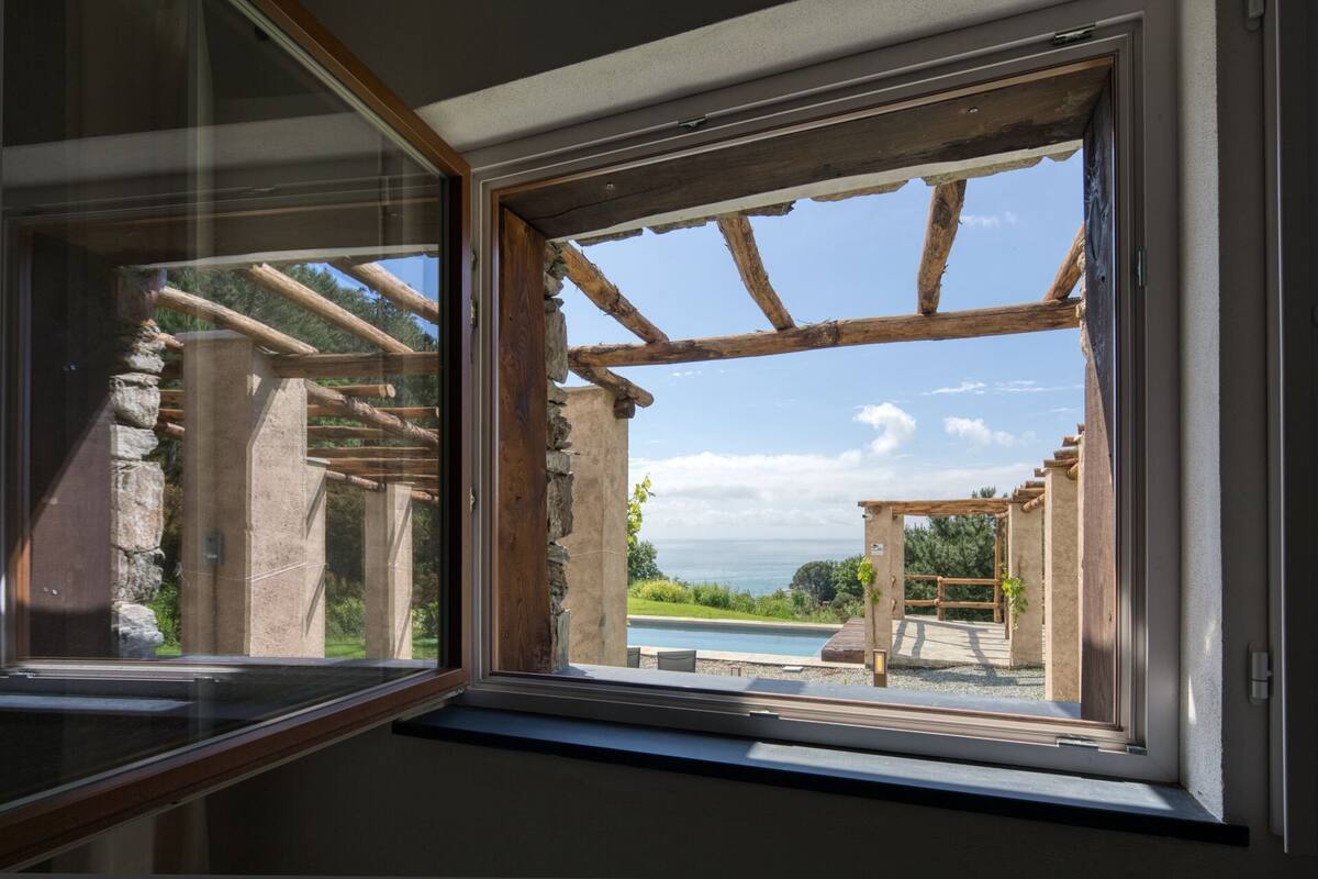 Une fenêtre donnant sur une pergola en bois et une piscine.