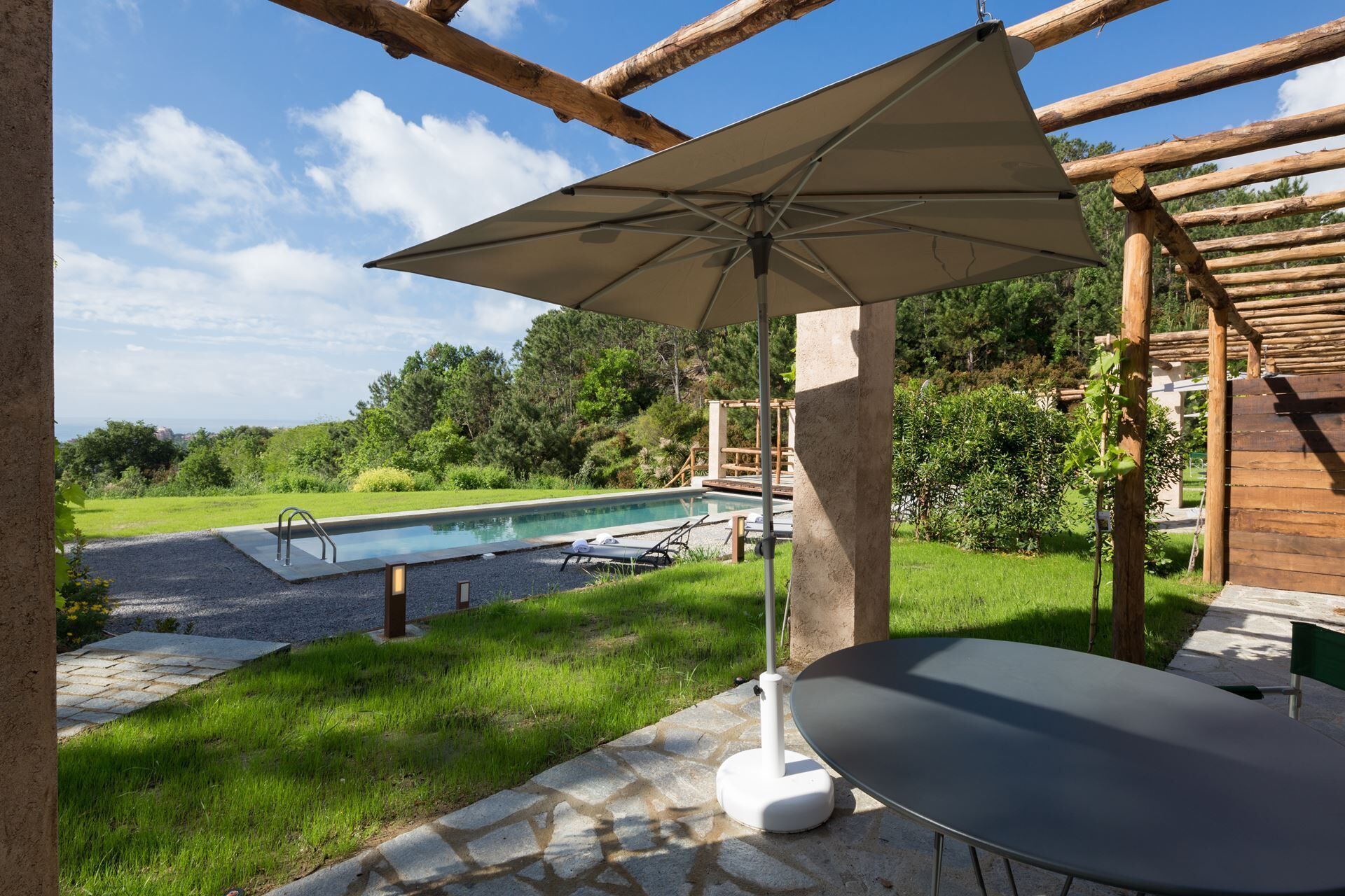 Un espace patio avec une piscine, une table et un parasol.