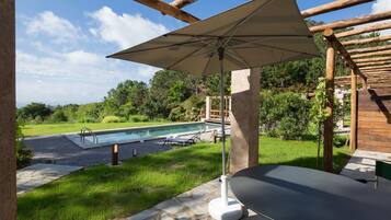 Un espace patio avec une piscine, une table et un parasol.