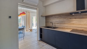 Una cocina moderna con salpicadero de madera, un lavamanos negro y armarios oscuros.