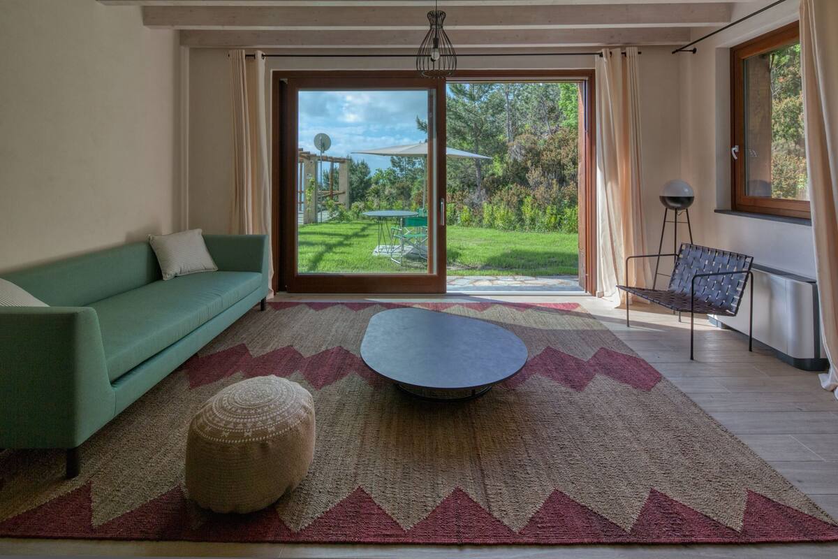 Un salon moderne avec un canapé vert, une table basse ronde et un tapis à motifs.