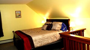 A single bed with a headboard, two bedside lamps, and a small framed picture on the wall. - Large 1 bed w/ private deck (Portland)