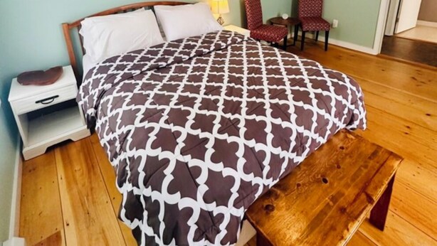 A bedroom with a wooden bed, a nightstand, a bench, a chair, and a ceiling with a light fixture. - Studio Apartment near downtown Walkable! (Portland)
