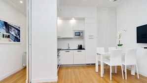 A modern kitchen with white cabinets, a microwave, and a dining area with white chairs and a table. - 2 apartments in the same building 2+3 (Spanish steps) (Roma)