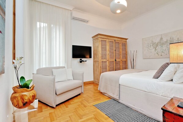 A modern hotel room with a sofa, a bed, a TV, a wardrobe, and a potted plant. - 2 apartments in the same building 2+3 (Spanish steps) (Roma)