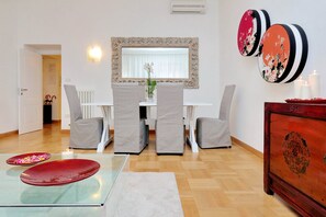 A dining area with a white table, grey chairs, a glass table with red plates, a white rug, and a wooden cabinet with a mirror and decorative plates. - 2 apartments in the same building 2+3 (Spanish steps) (Roma)