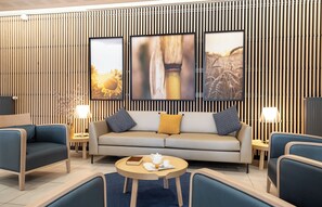 Una sala moderna con un sofá, dos sillones, una mesa de centro y un televisor montado en una pared de madera con listones verticales.