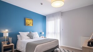 A modern bedroom with a bed, two bedside tables, a lamp, a picture frame, and a patterned rug. - Zenao Appart'hôtels Toulouse Balma (Balma)