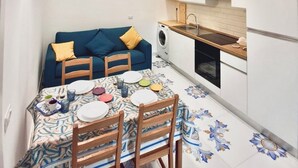Een compacte keuken met een eethoek, houten balken, een wasmachine en een kleine tafel gedekt voor vier personen.