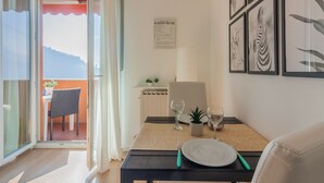 A dining area with a table set for two, a view of the outdoors, and a menu on the wall. - Roberta's Home (Perledo)
