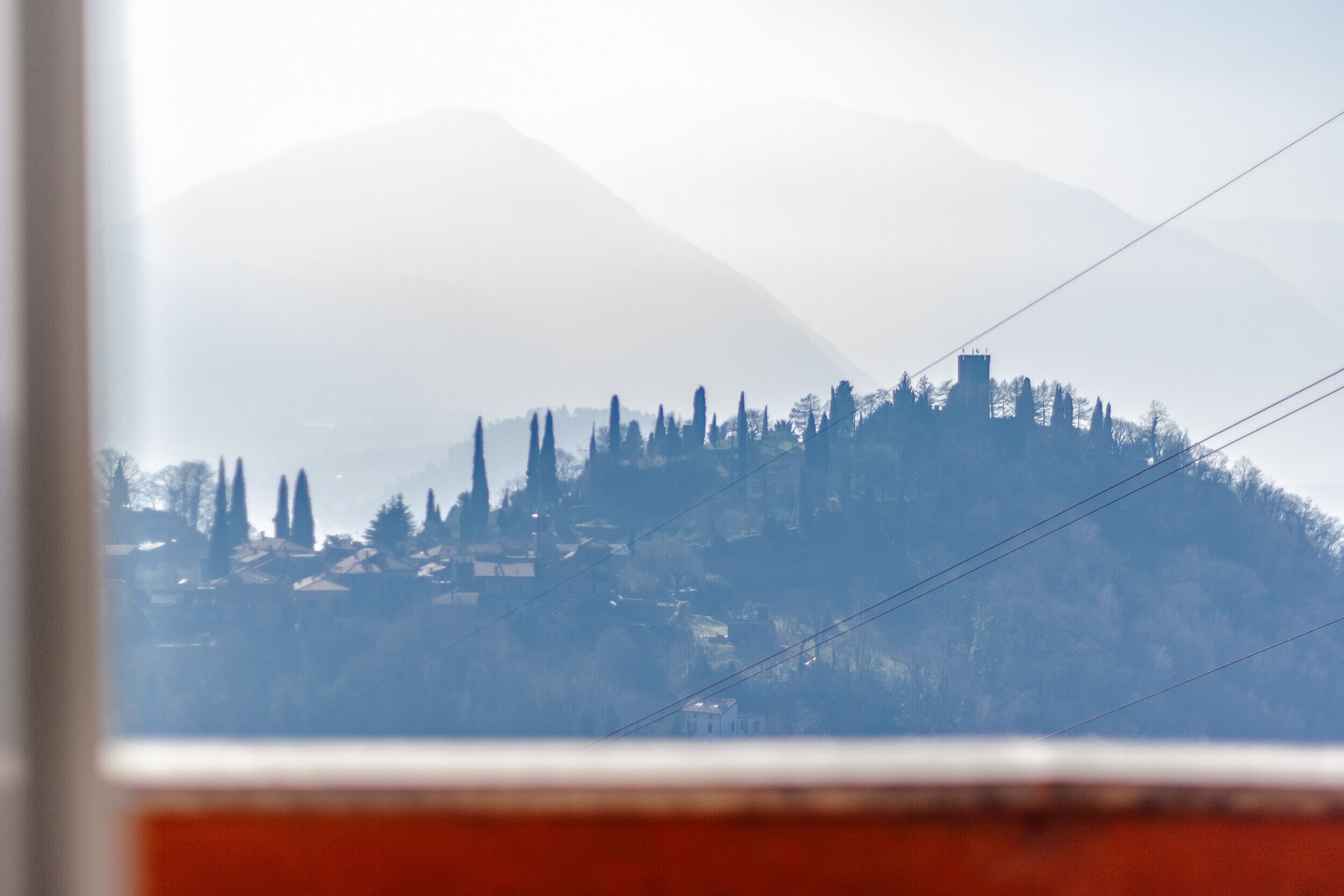 Paesaggio montano con alberi e un piccolo edificio.