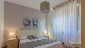 A bedroom with a bed, bedside tables, a lamp, a chair, and artwork on the wall. - Roberta's Home (Perledo)