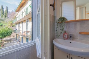 A bathroom with a sink, a mirror, and a window overlooking a balcony. - Corte al Castello by Varenna Holidays (Perledo)