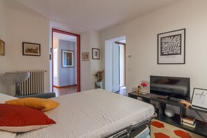 A bedroom with a bed, a TV, a radiator, and framed pictures on the wall. - Corte al Castello by Varenna Holidays (Perledo)