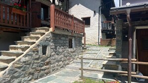 A stone staircase leading to a wooden balcony with a railing, a small window, and a door.