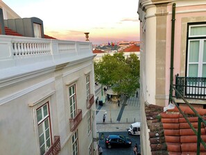 Una calle estrecha con edificios a ambos lados, un árbol en el centro y un coche estacionado.