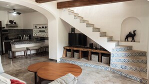 Amplia sala de estar con una mesa de centro de madera, un sofá y una cocina al fondo.