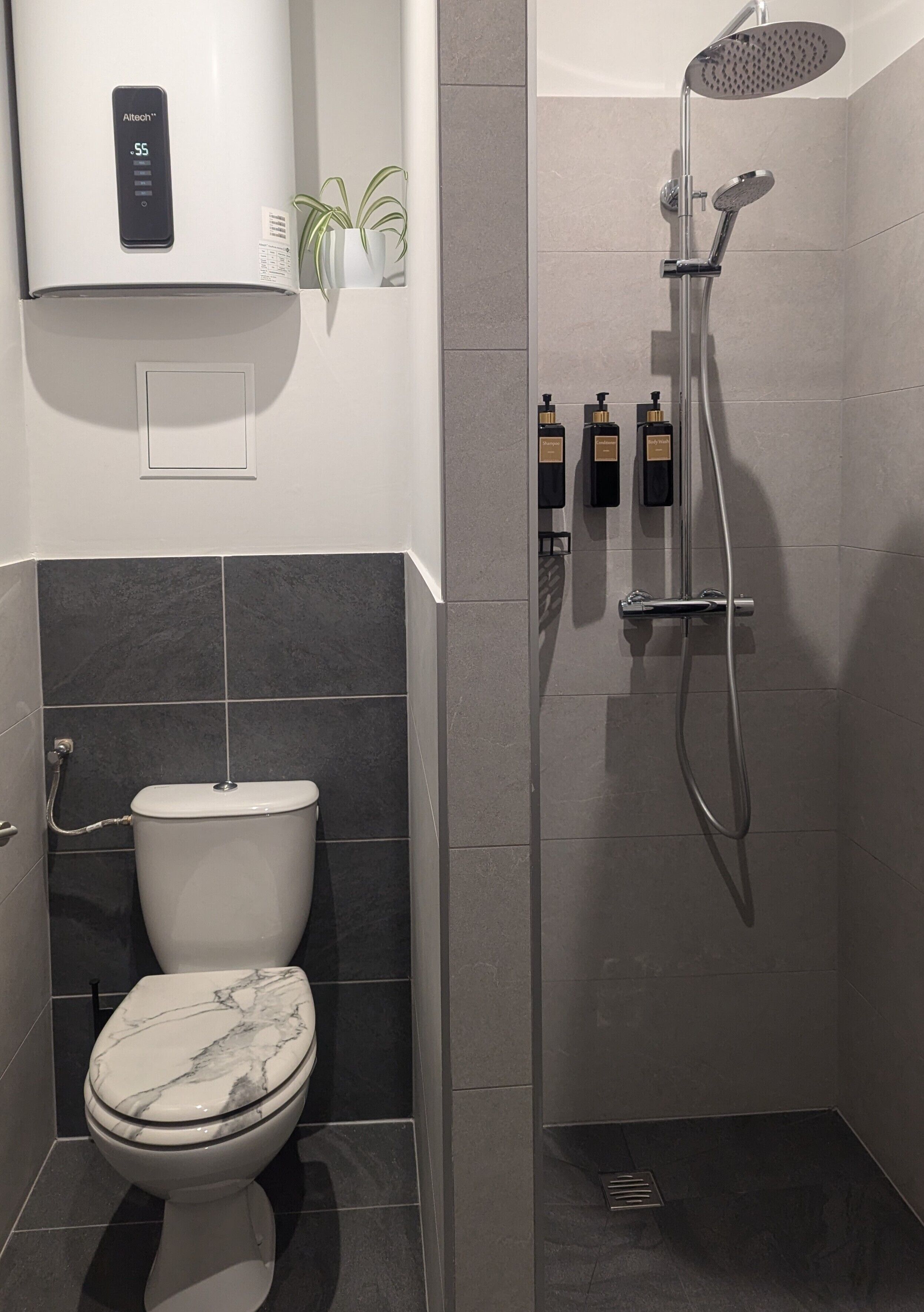 A bathroom with a toilet, a shower, and a water heater.