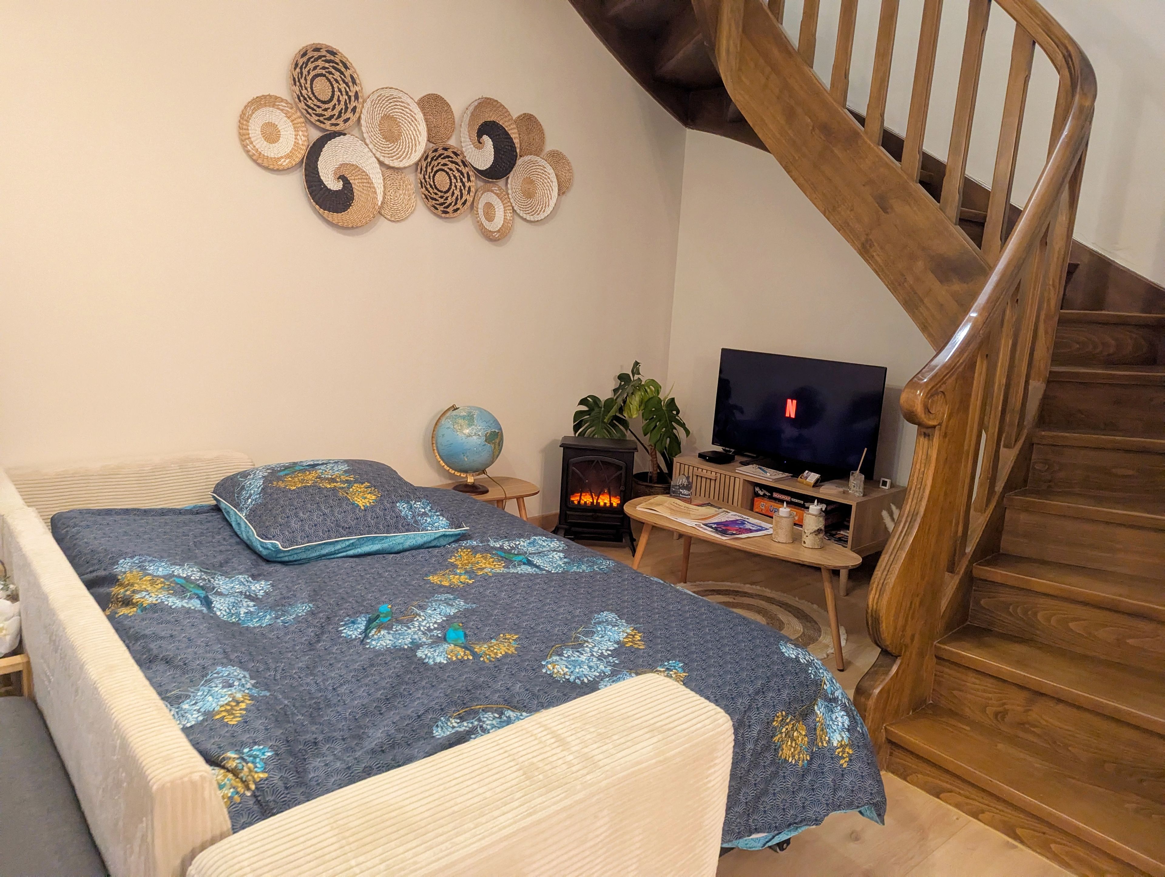A cozy bedroom with a bed, a wooden staircase, a television, and a small table with a globe.