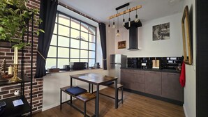 A modern kitchen with a dining table, a large window, and a brick wall.