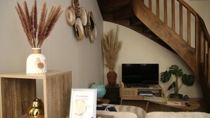 A living room with a wooden staircase, a globe, a television, and a plant.