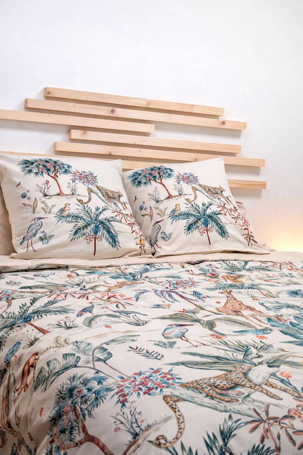 A bed with a patterned bedspread and two pillows with a nature-themed design.