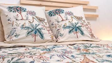 A bed with a patterned bedspread and two pillows with a nature-themed design.
