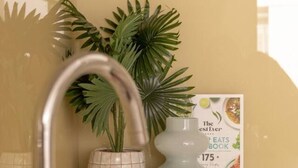 A bathroom with a modern sink, a potted plant, and a book titled "The Essential Ever EATS BOOK". - Coastal Retreat Steps to Beach (Port Melbourne)
