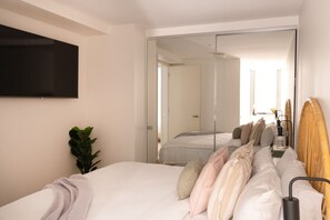 A modern bedroom with a bed, a TV, a mirror, and a plant. - Coastal Retreat Steps to Beach (Port Melbourne)