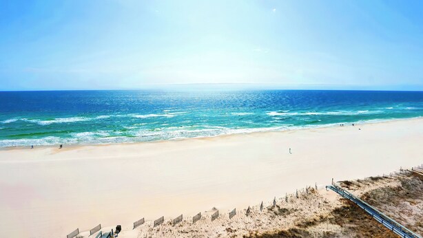 Ein Strand mit blauem Himmel, ruhiger See und sandigem Ufer.
