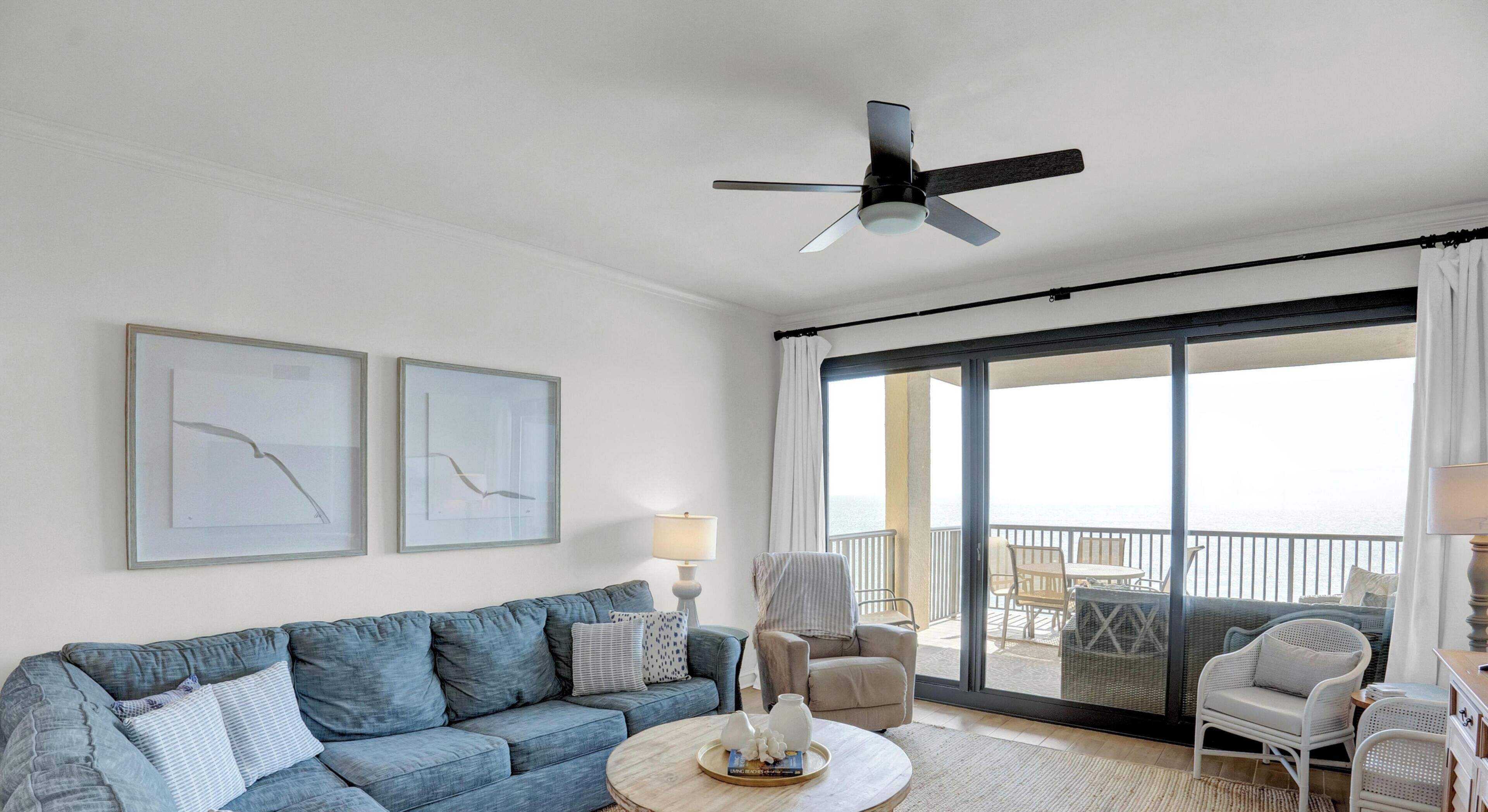 Un salon comprenant un canapé, des fauteuils, une table basse et un ventilateur de plafond.