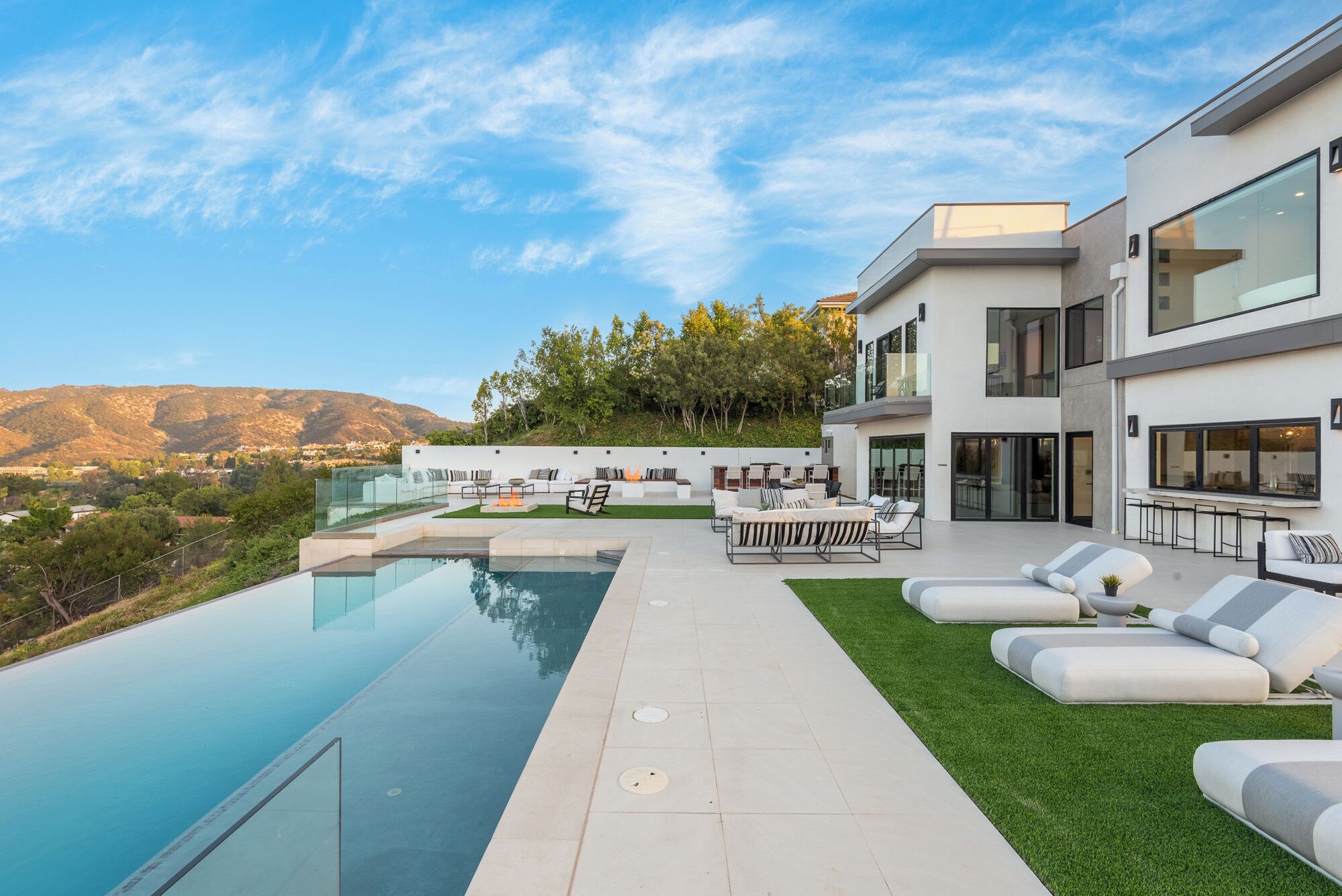 Una casa moderna con piscina, mobiliario exterior y vistas a la montaña.