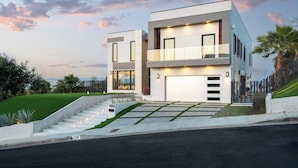 A modern two-story house with a garage, a well-maintained lawn, and a staircase leading to the entrance. - Gayle Villa - Stunning Modern Masterpiece with Breathtaking Views (Los Angeles)