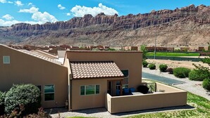 A residential building with a tiled roof, a small porch, and a view of a mountainous landscape.