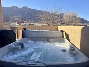 Un bain à remous avec vue sur les montagnes et un espace clos agrémenté d’arbres.